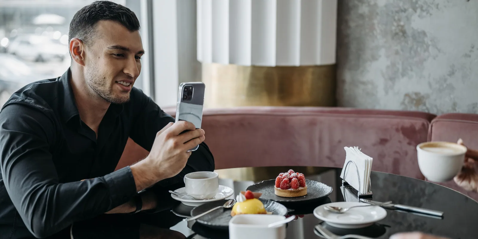 A customer at a café table using his phone after the meal.