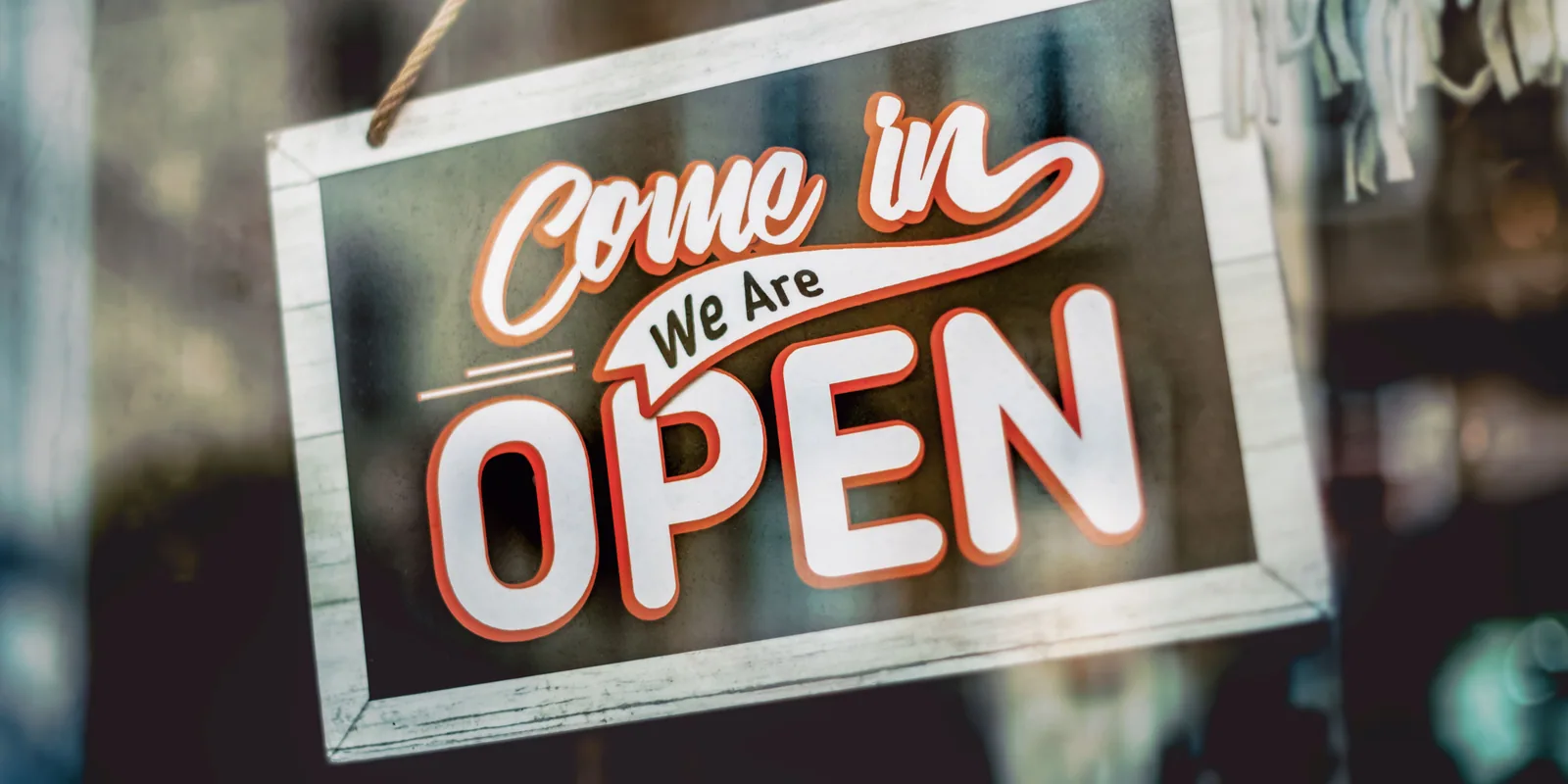 An "Open" sign hanging in a shop window.