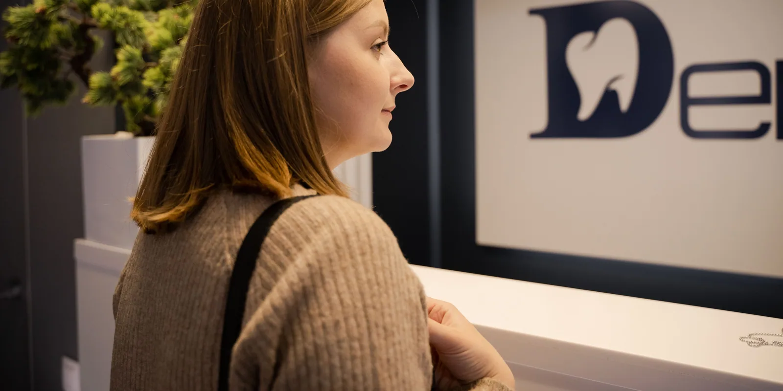 A patient waiting at the front desk of a dental clinic.