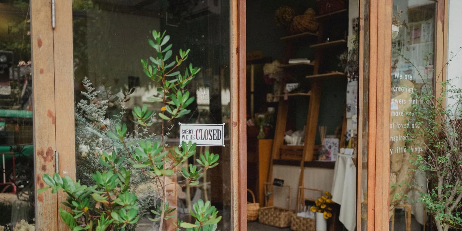 A florist’s glass door with a “Sorry, we’re closed” sign hanging in it.